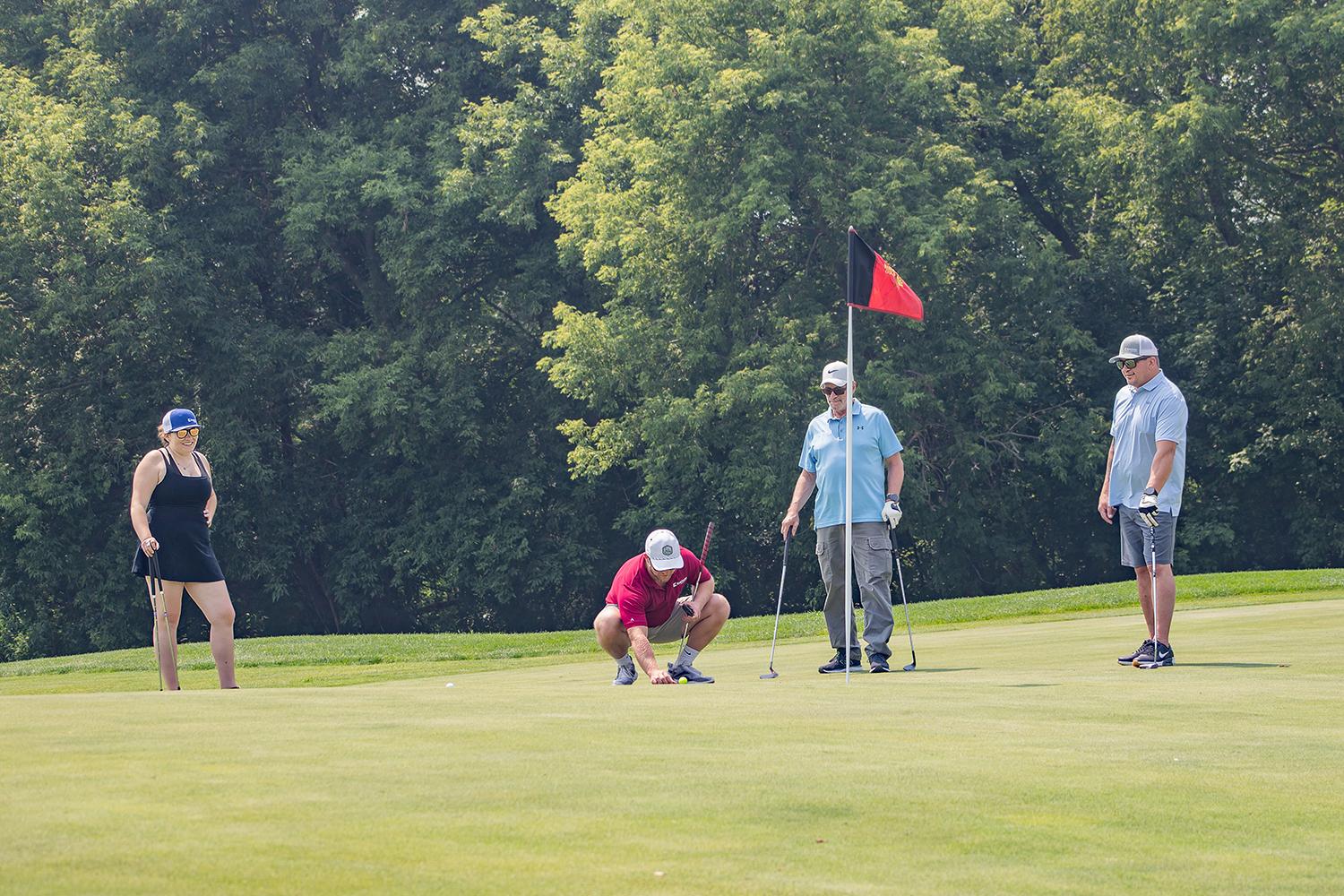 photo of a foursome team member lining a putt up